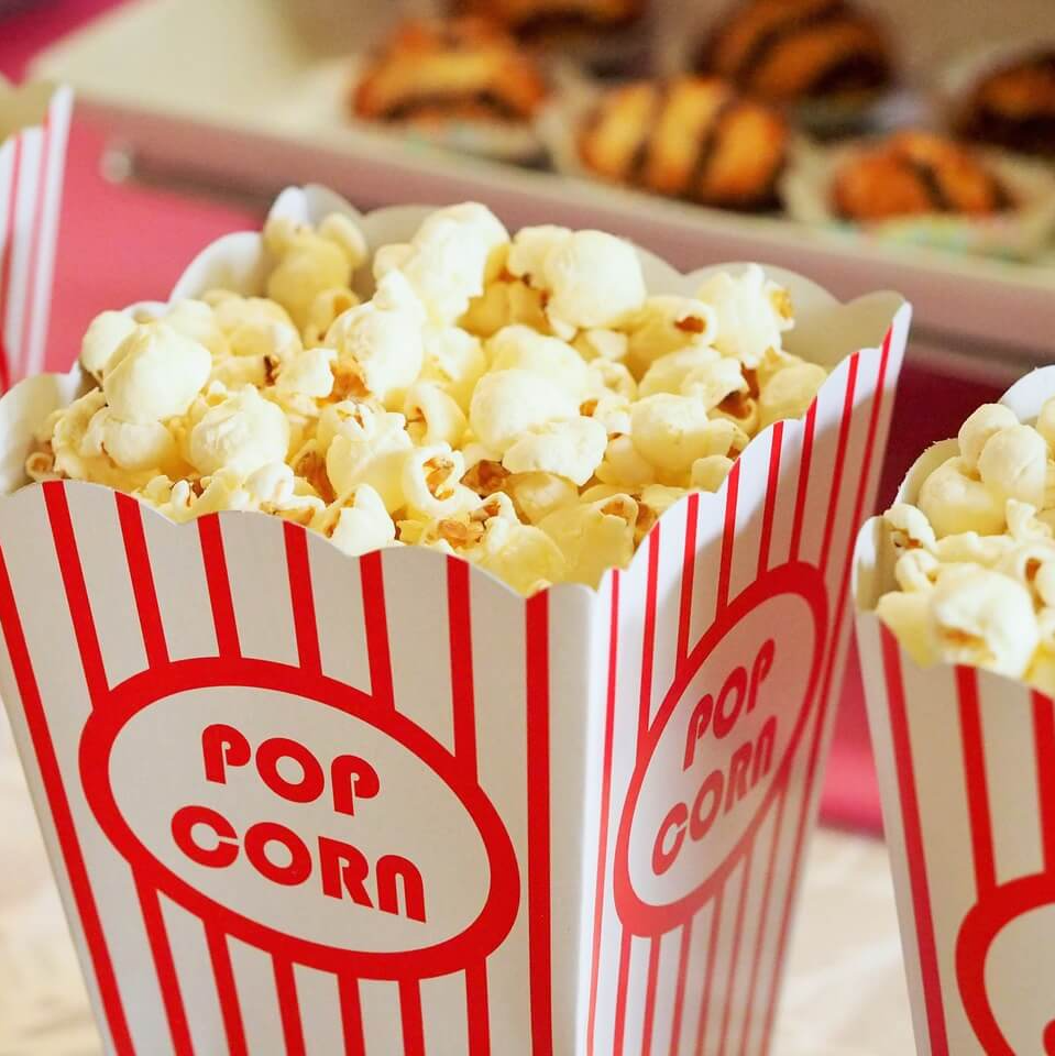 A red and white striped container of pop corn from Conrad's Concessions