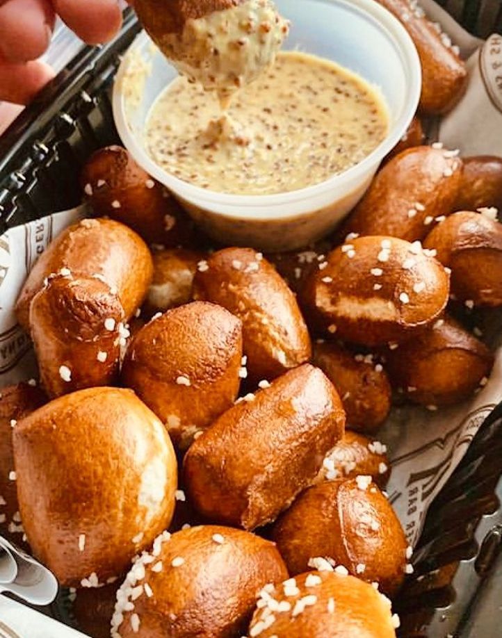 A person is dipping a pretzel into a dipping sauce