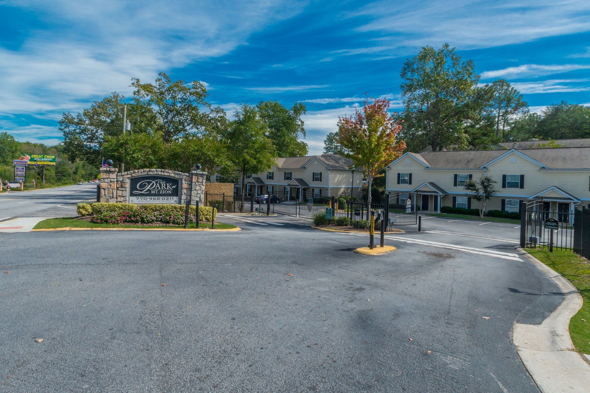 A paved driveway leads to a stone entrance sign for 