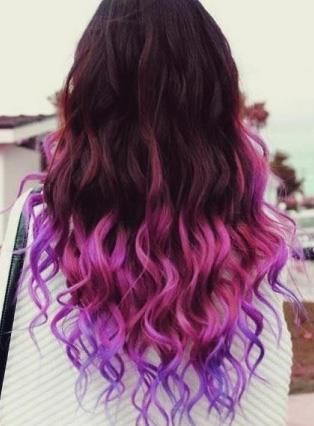 A woman with bright pink hair is sitting in a chair in a salon.