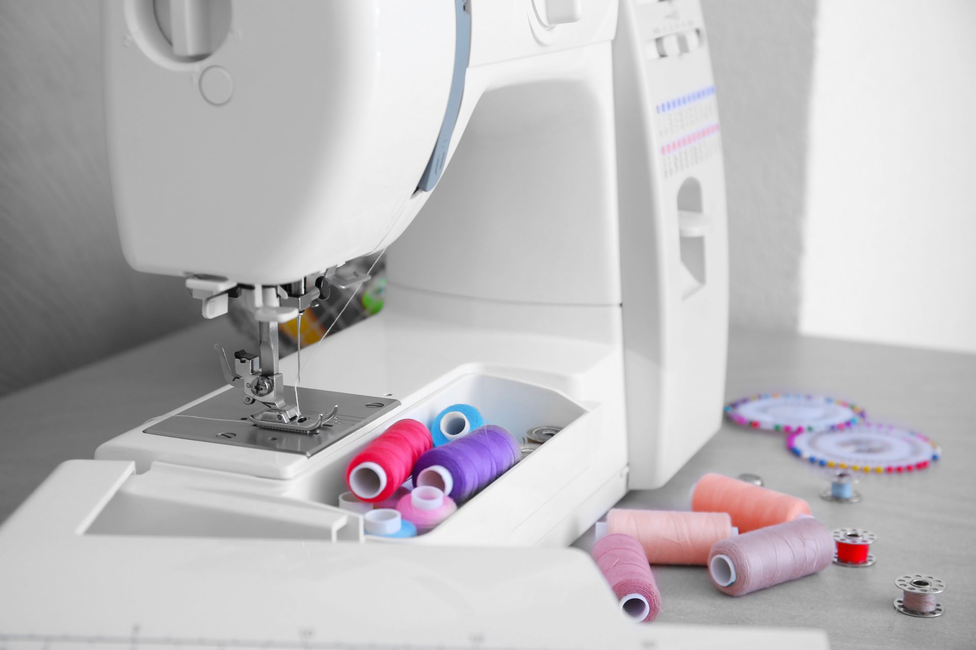 Sewing machine with colorful thread spools and fabric on a sewing table