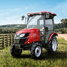 Red tractor on grass in a rural field with hills and blue sky in the background