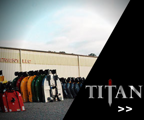 Row of colorful tractor attachments outside a warehouse with TITAN logo on the right