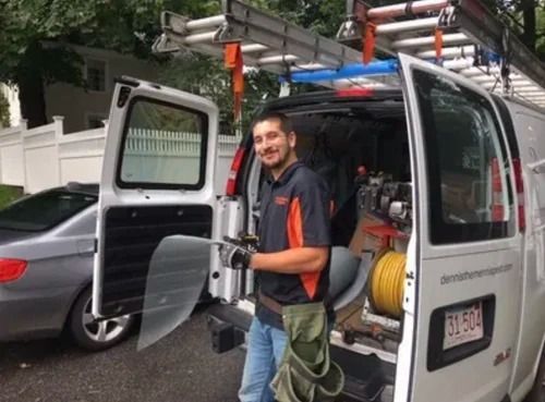 Worker standing by open utility van with ladder and equipment on a residential street
