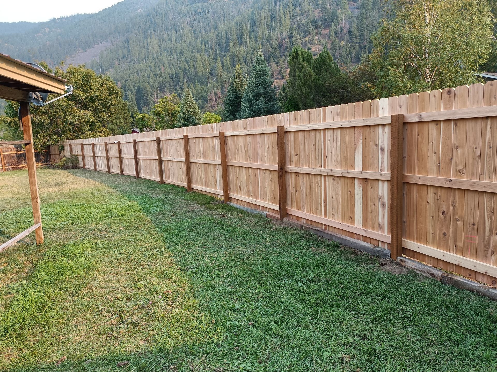 A wooden fence is in front of a large white house.