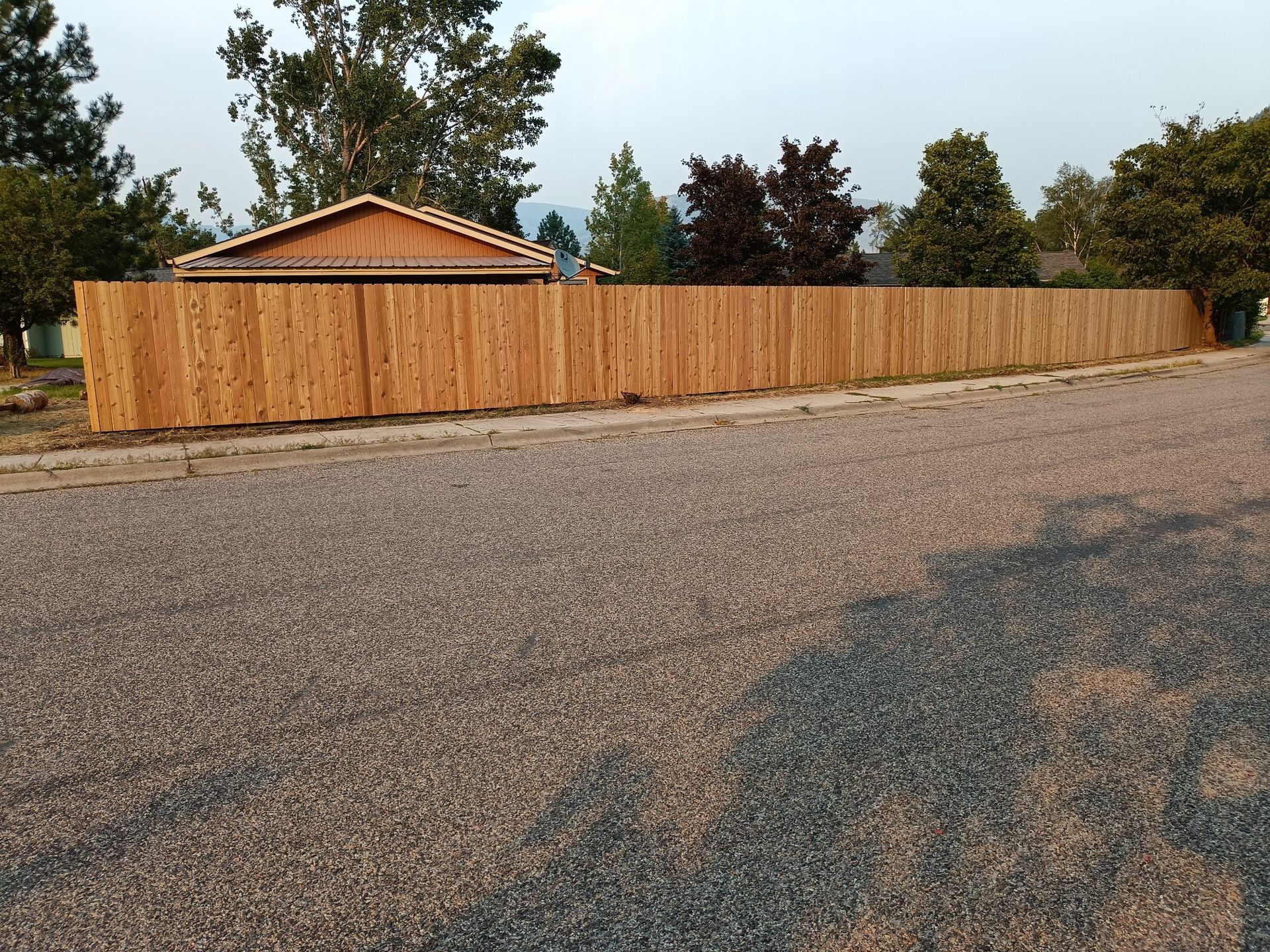 A wooden fence with a gate and trees in the background.