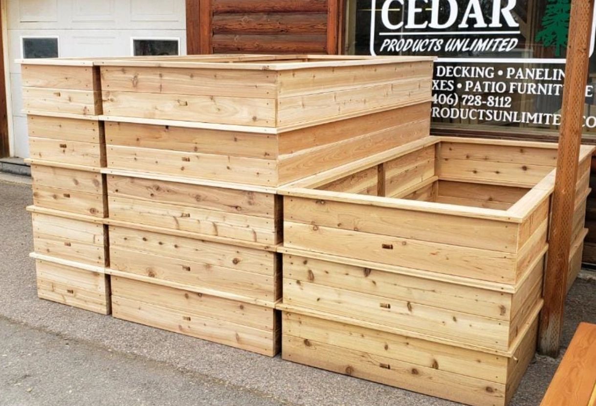 A stack of wooden boxes sitting on top of each other in front of a cedar sign.