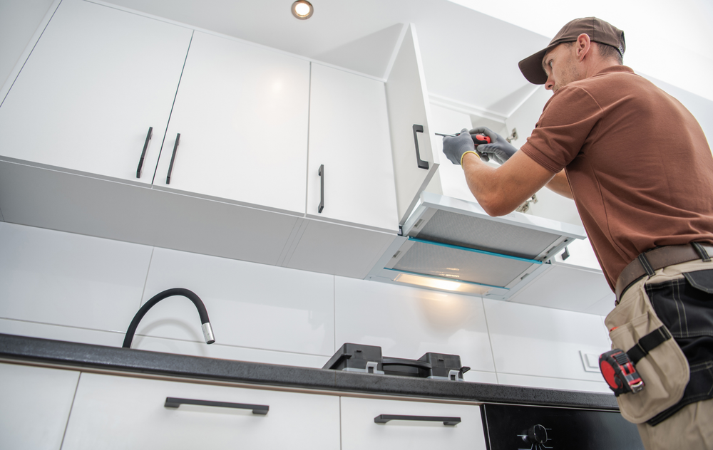 A man is installing a hood in a kitchen.