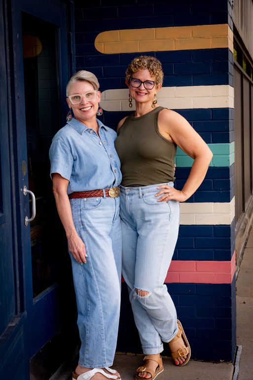 Two women are standing next to each other in front of a sign that says a mark was made.