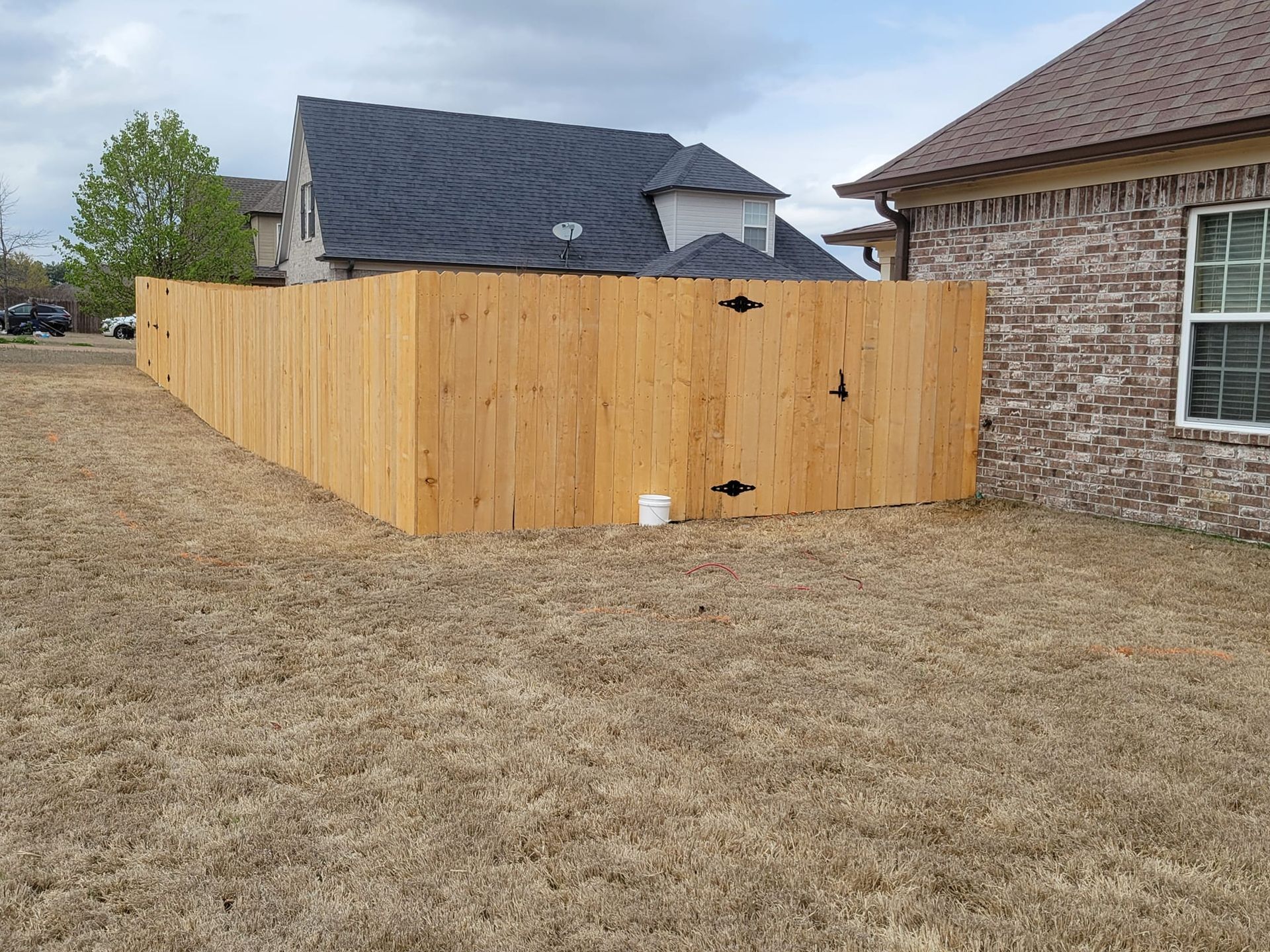 A wooden fence is in the backyard of a house.