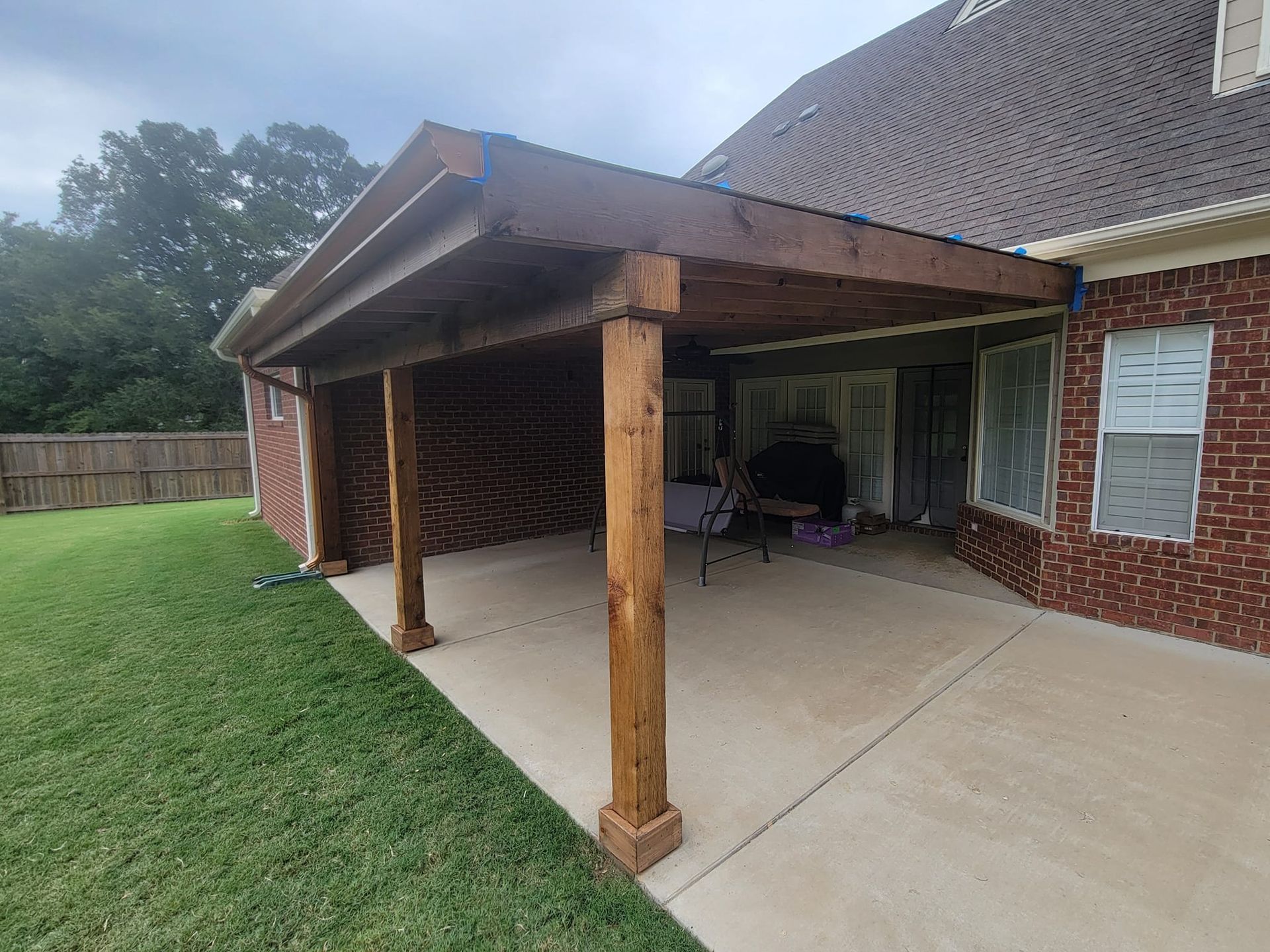 A brick house with a wooden covered patio in the backyard.