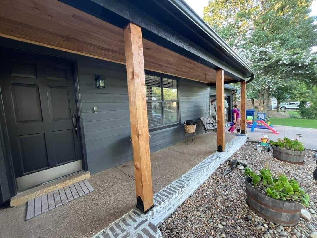 A black house with a porch and a playground in the background.