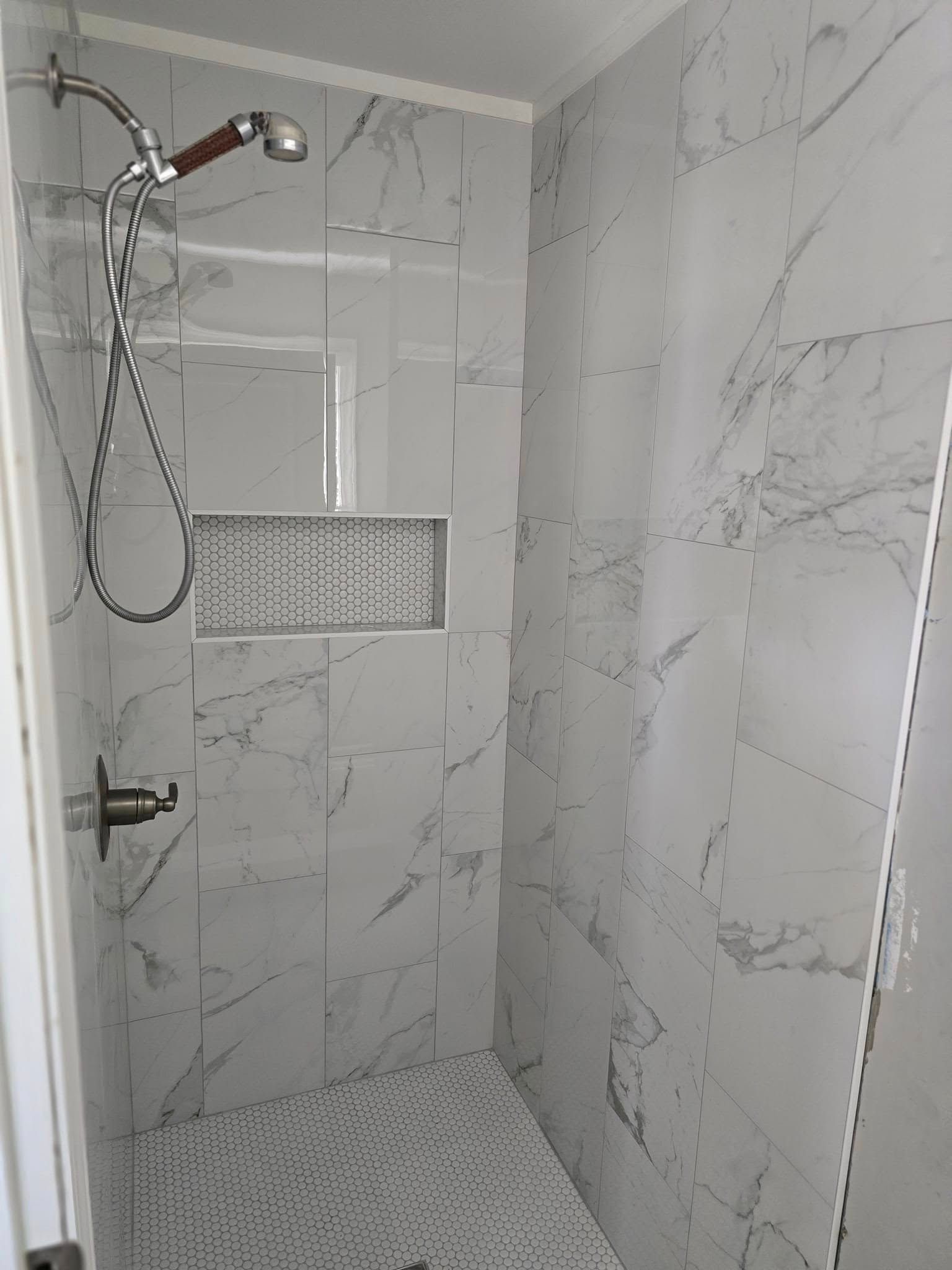 A shower with marble tiles and a shower head.