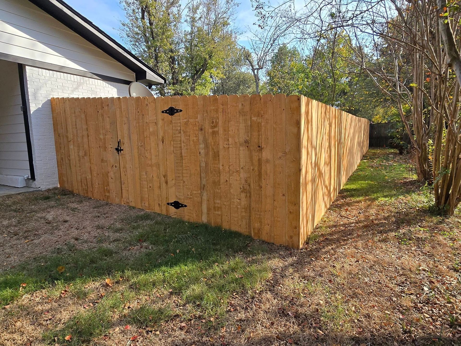 A wooden fence is in the backyard of a house.