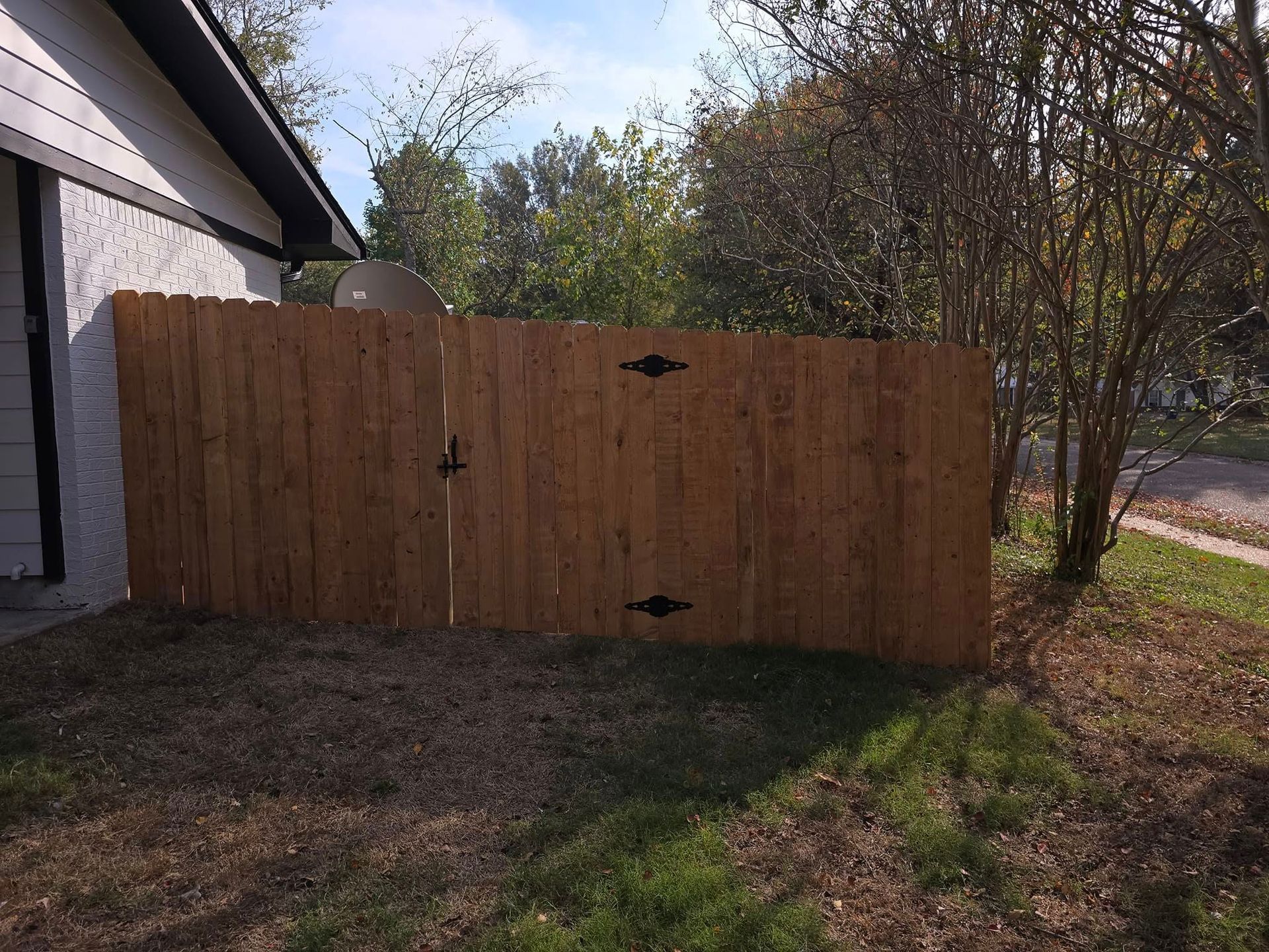 A wooden fence with a gate in the backyard of a house.