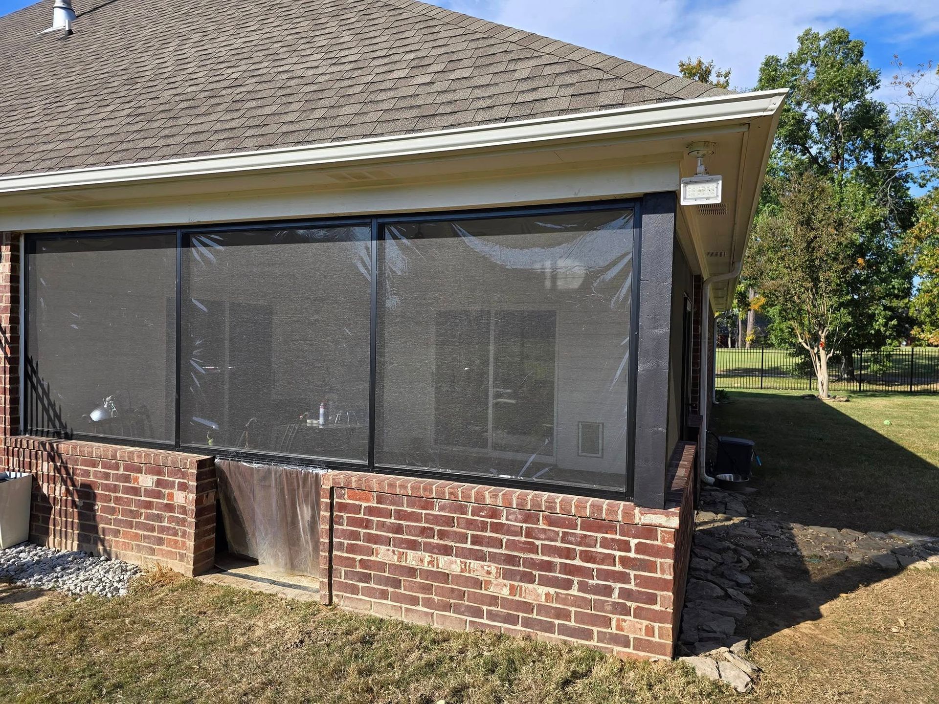 A screened in porch on the side of a brick house.