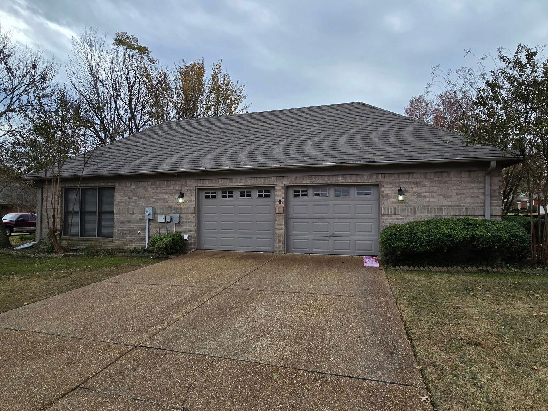 A brick house with two garage doors and a driveway