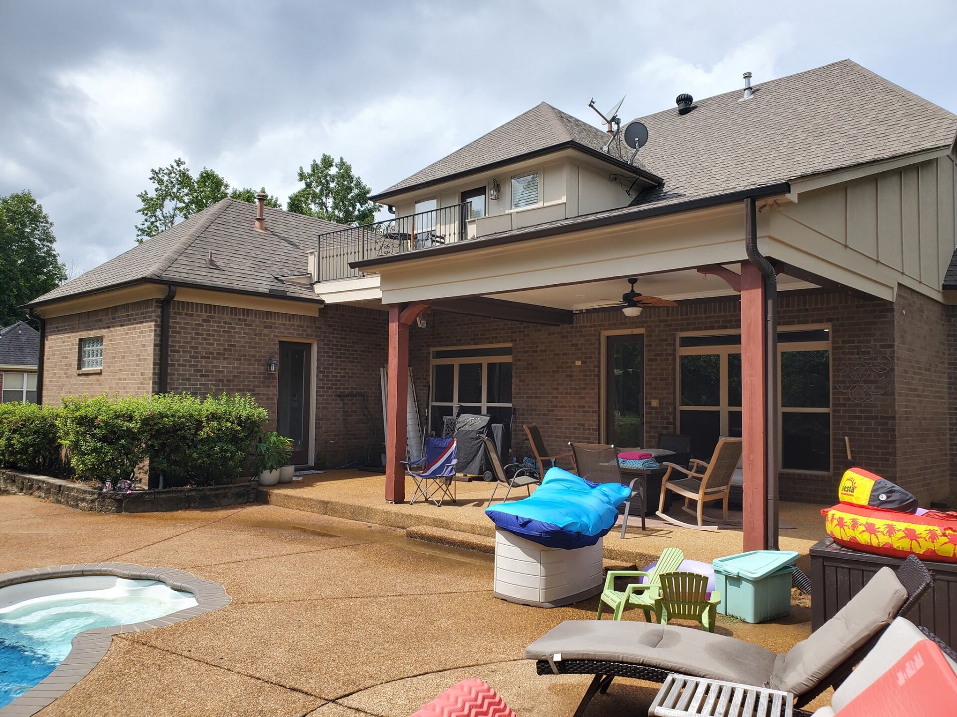A large brick house with a covered patio and a pool