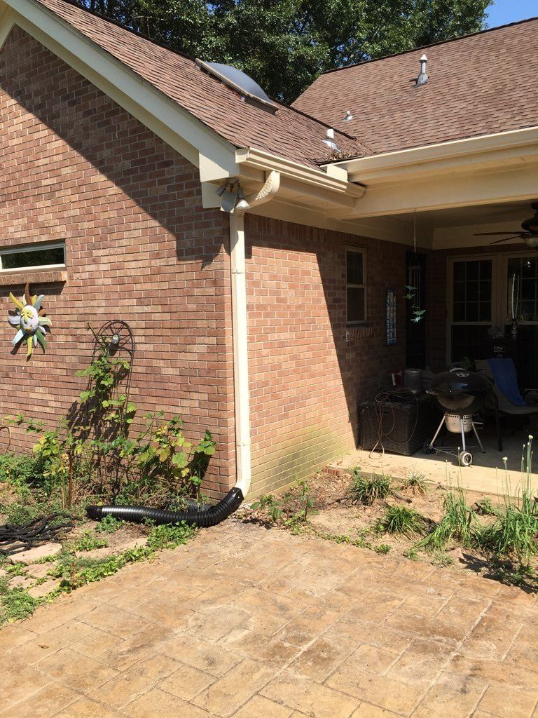 A brick house with a patio and a drainpipe on the side of it.