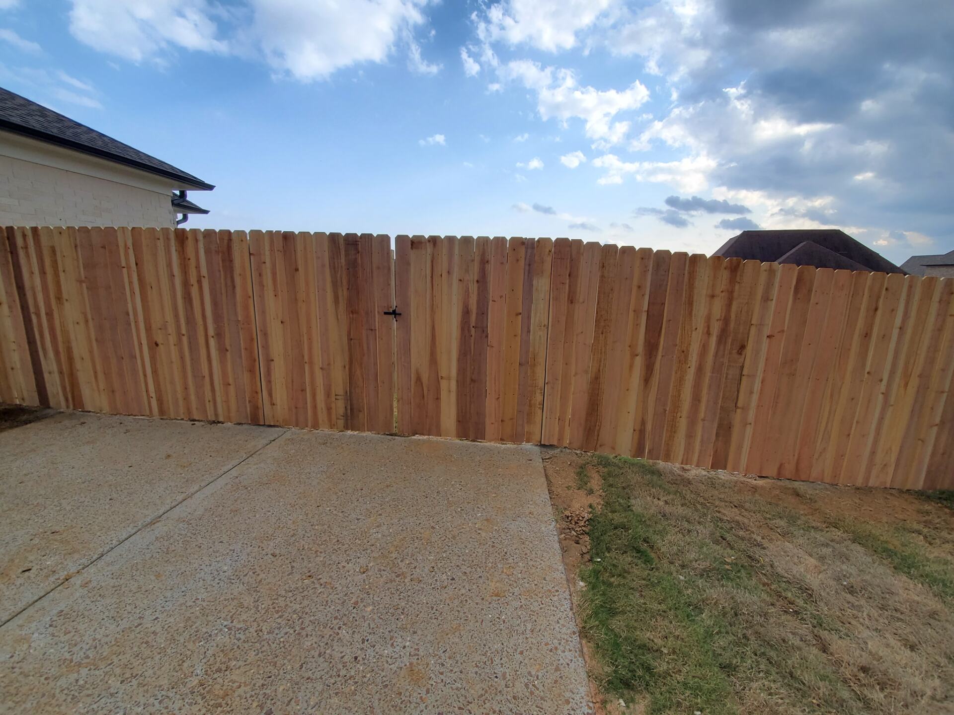 A wooden fence with a gate in the backyard of a house.