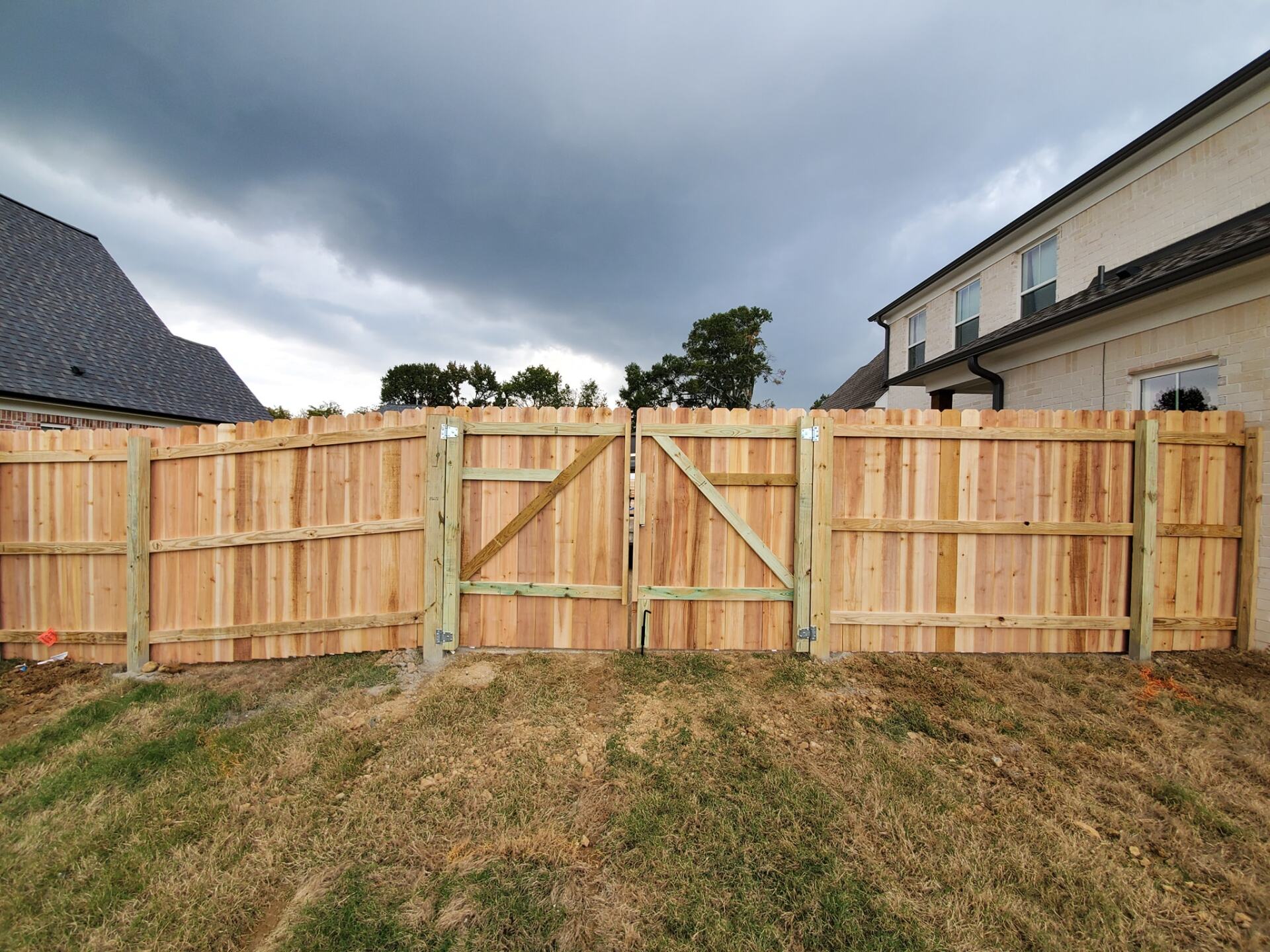 A wooden fence with a gate in the backyard of a house.