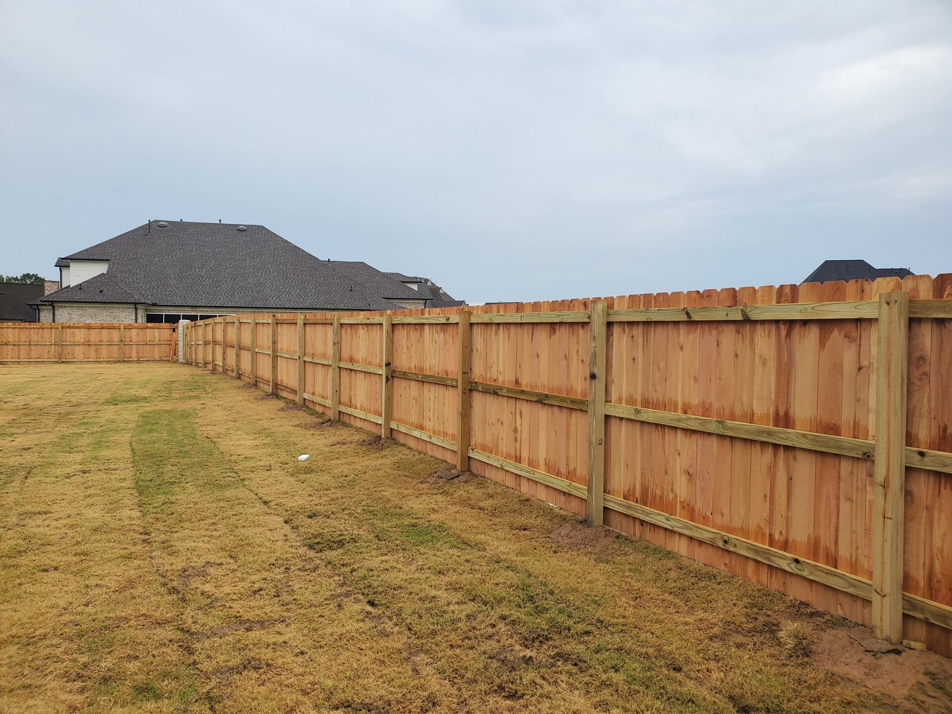 A wooden fence is in the backyard of a house.