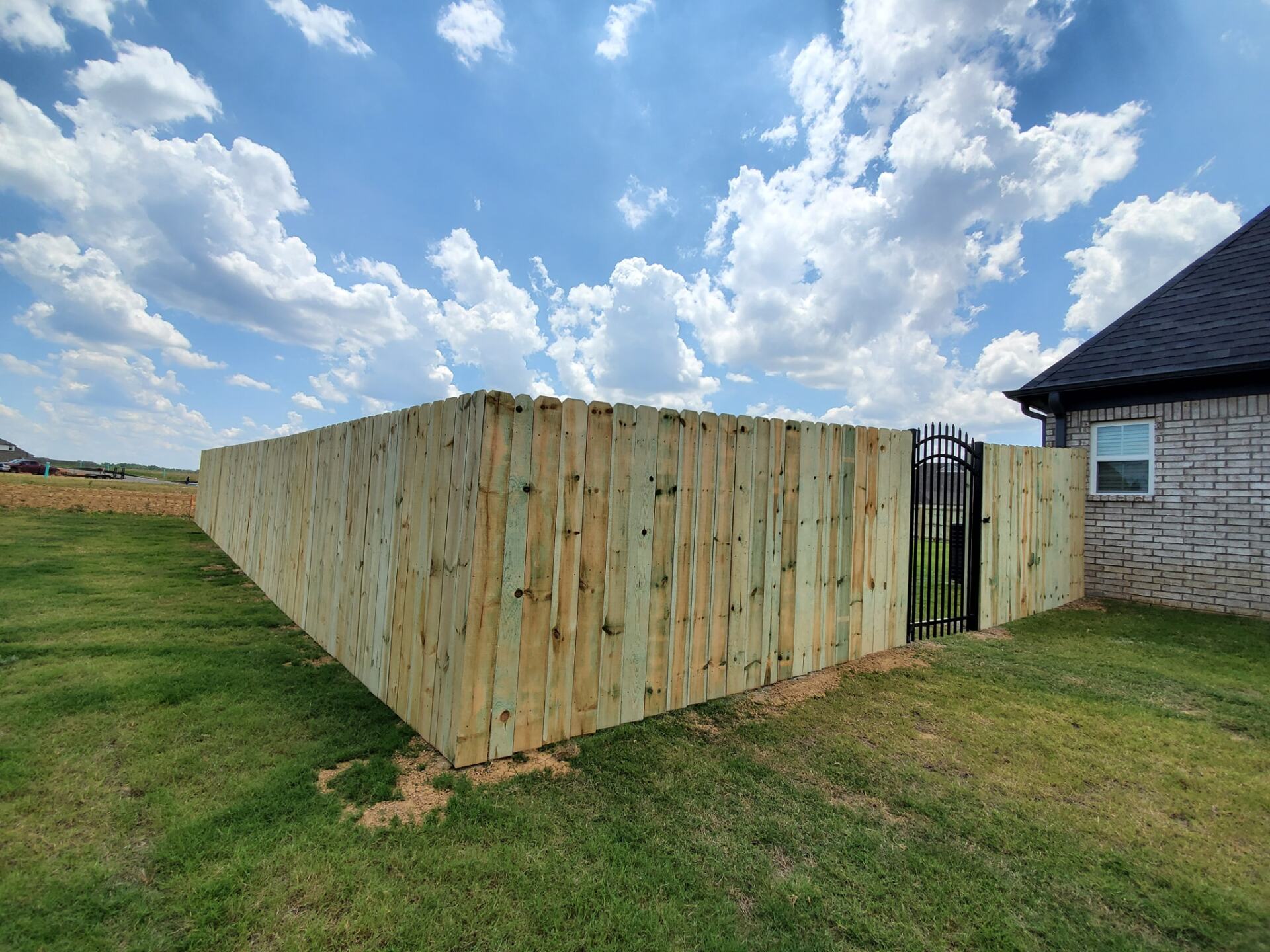 A wooden fence with a gate in the backyard of a house.
