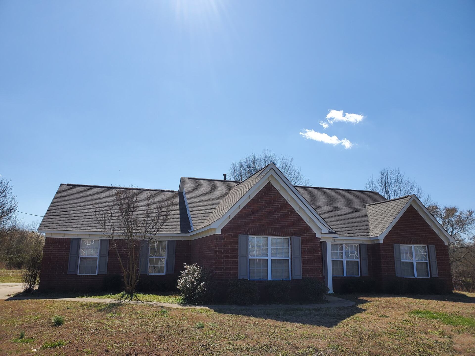 A brick house with a gray roof and white shutters