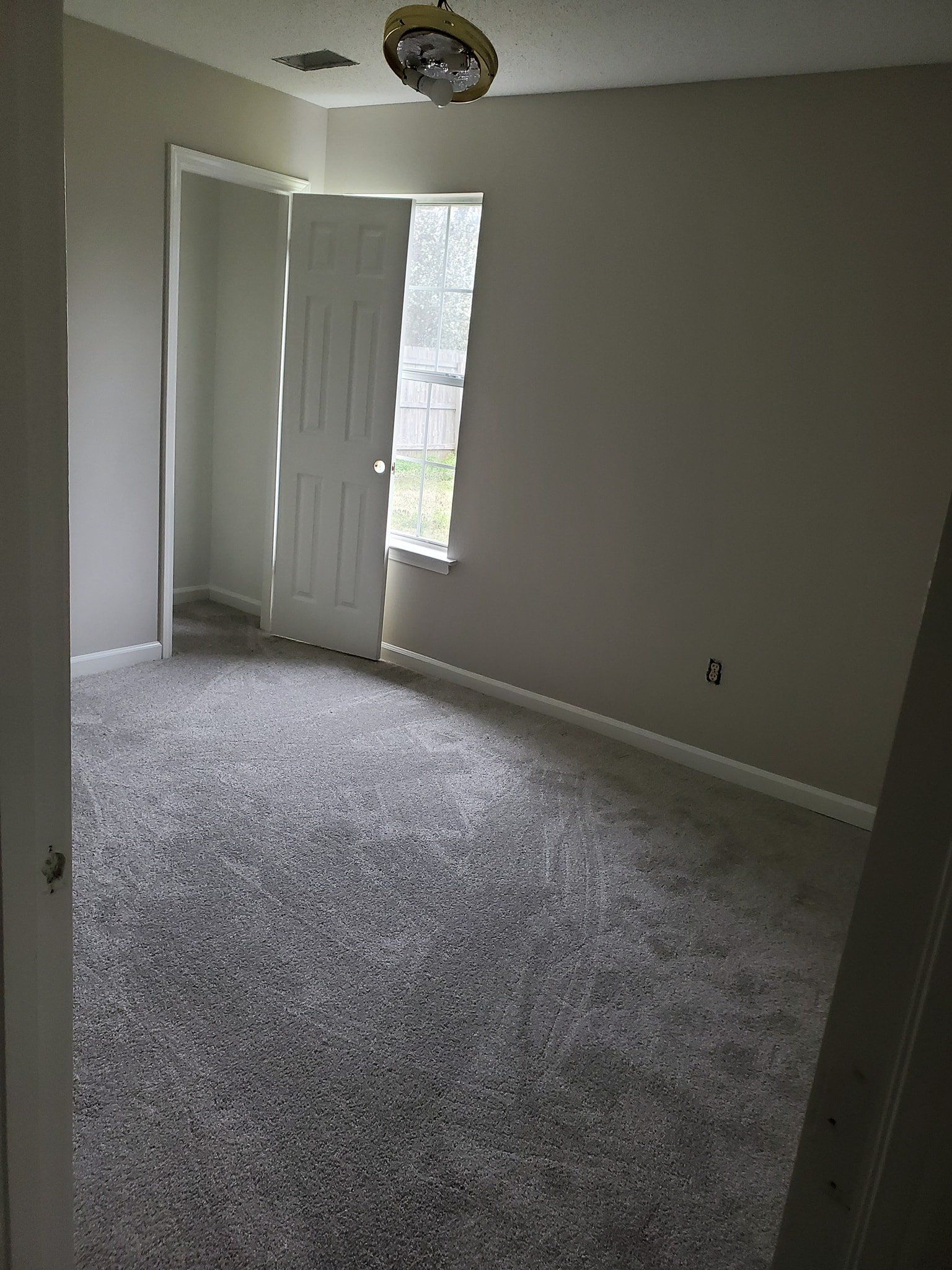 An empty bedroom with a ceiling fan and a window.