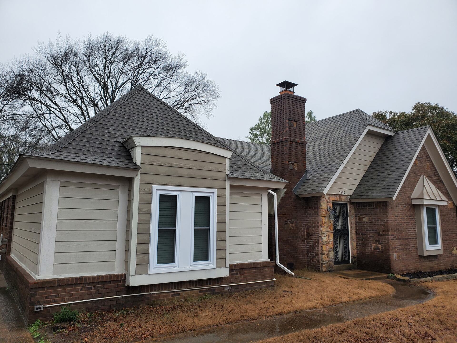 A small brick house with a chimney on the roof.