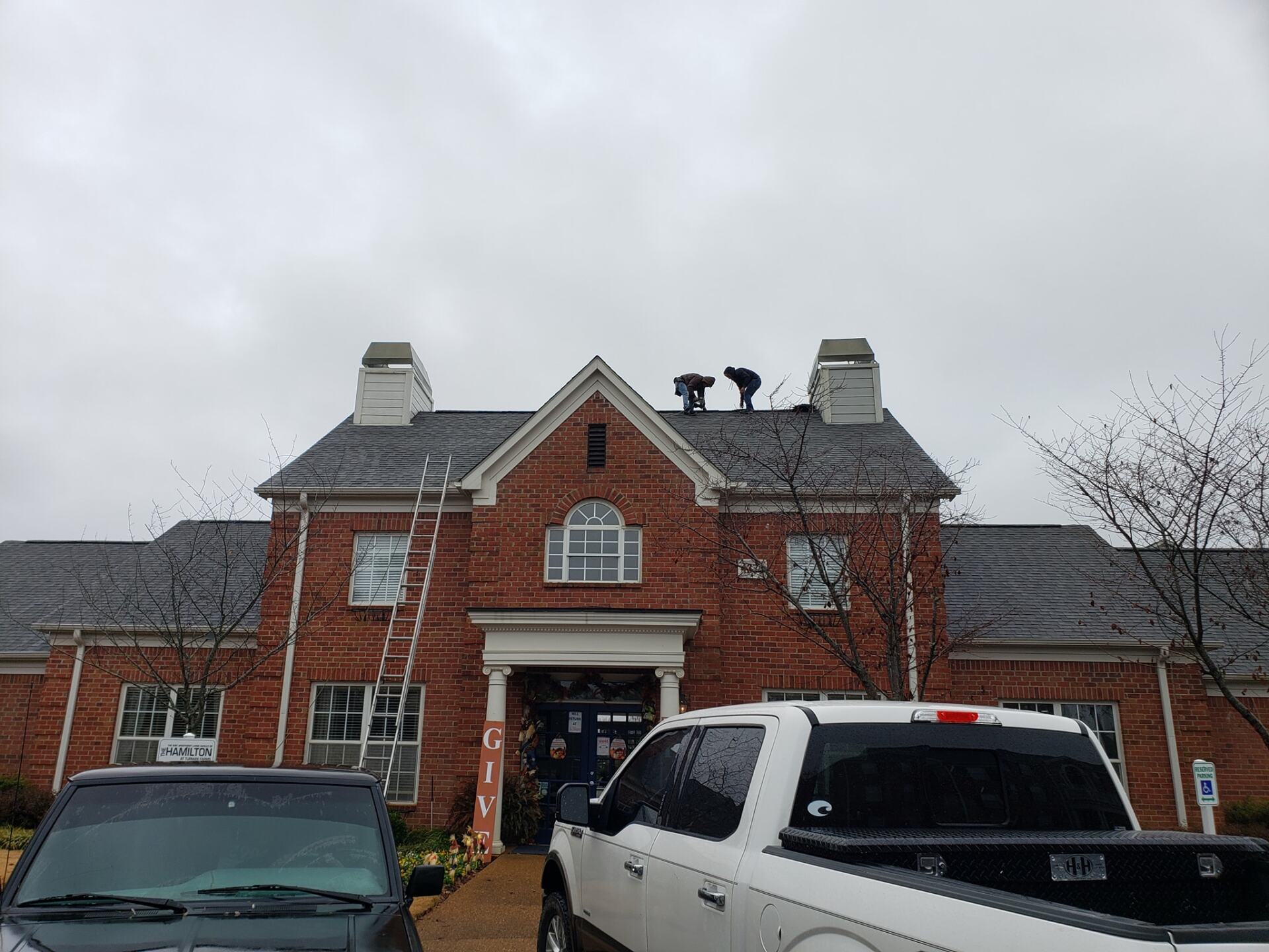 A white truck is parked in front of a large brick building.