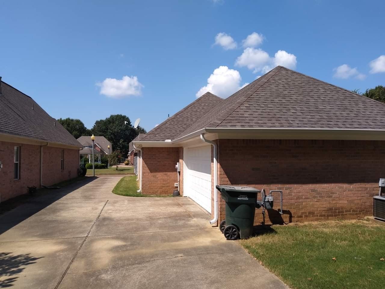 A brick house with a green trash can in front of it