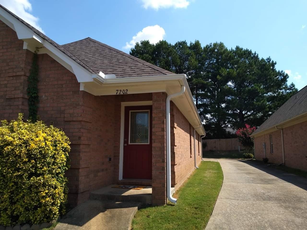 A brick house with a red door and a driveway