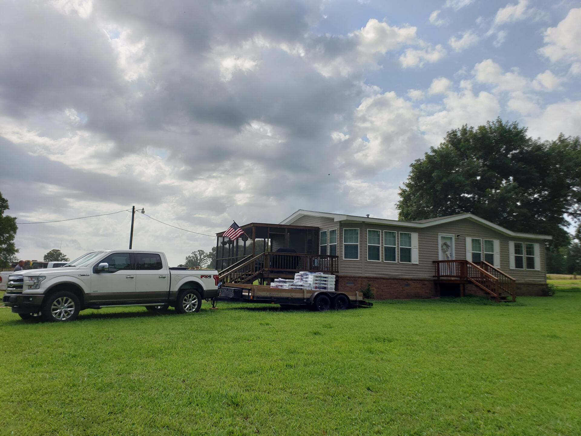 A truck is towing a trailer in front of a mobile home.