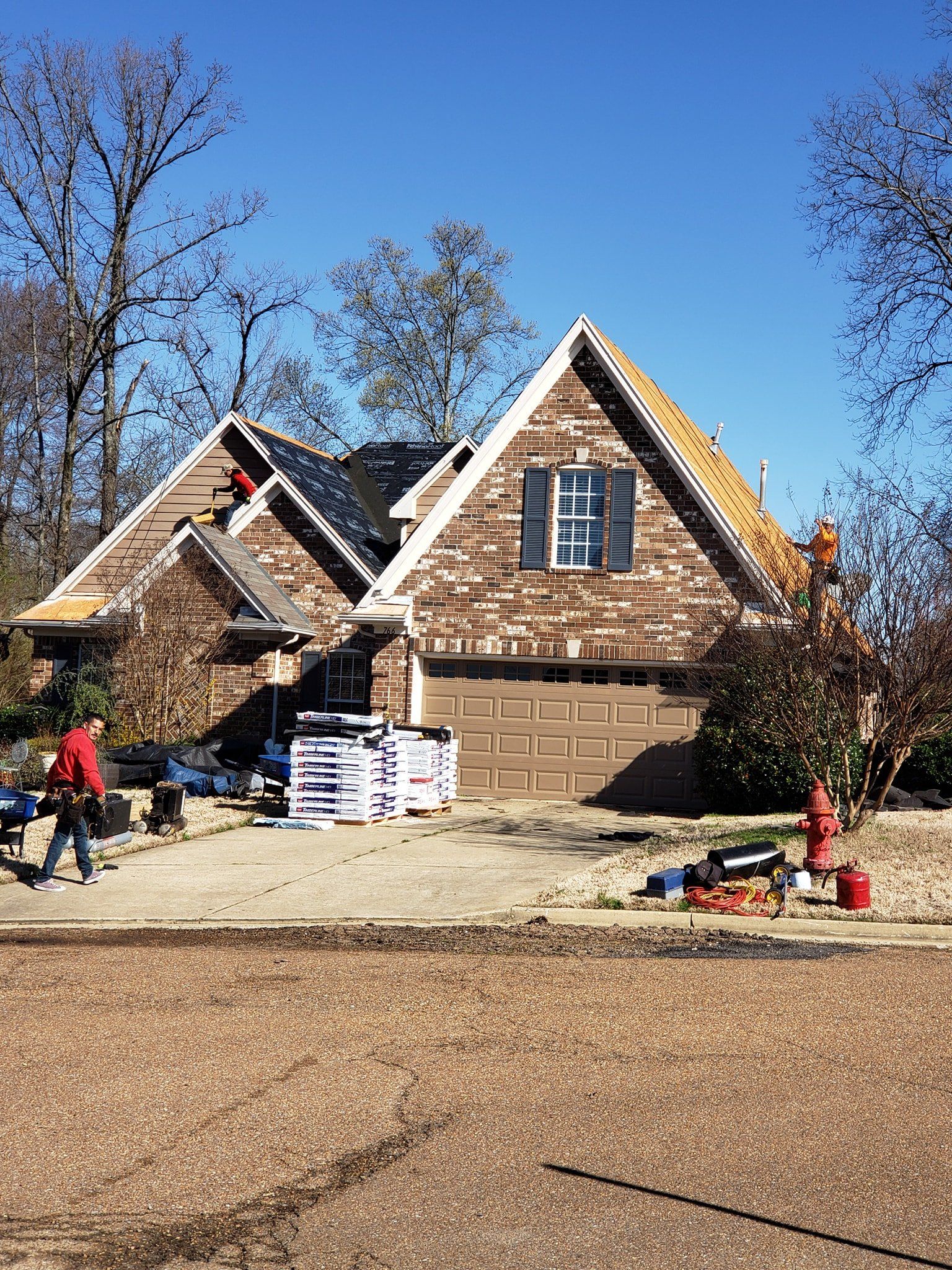 A brick house is being remodeled with a new roof.