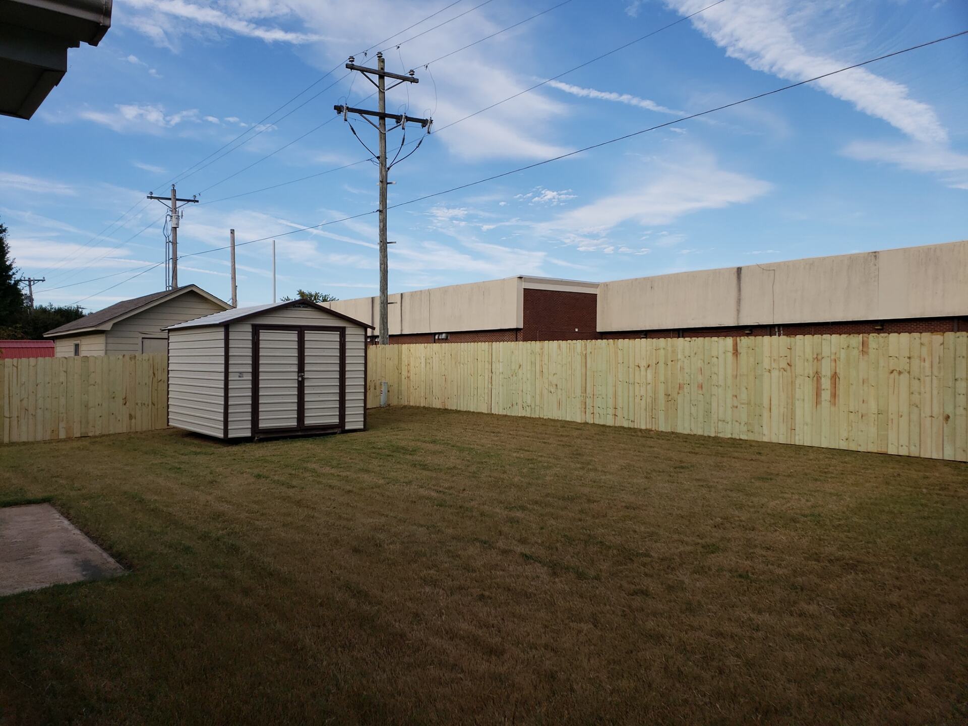 A backyard with a wooden fence and a shed