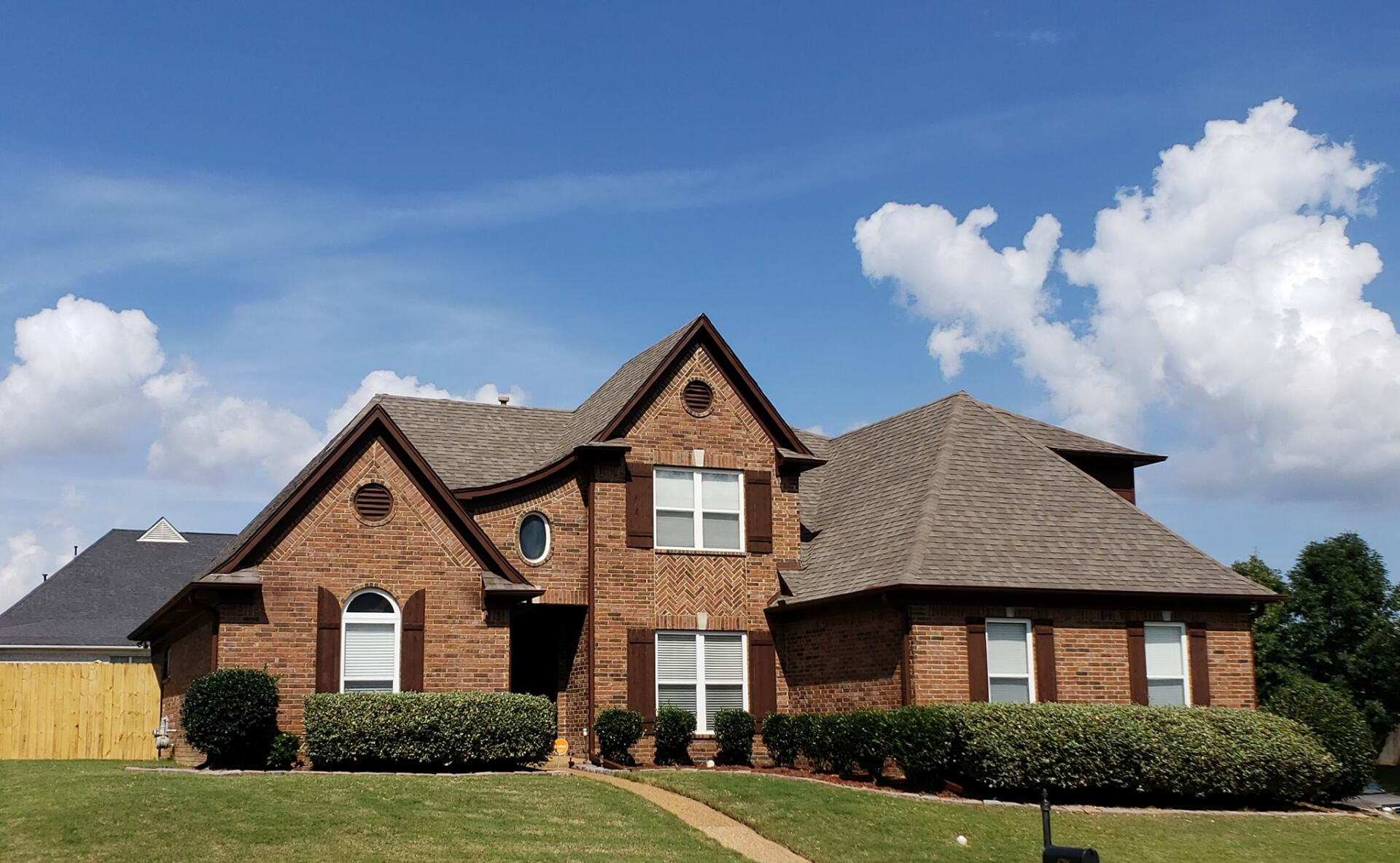 A large brick house with a blue sky in the background
