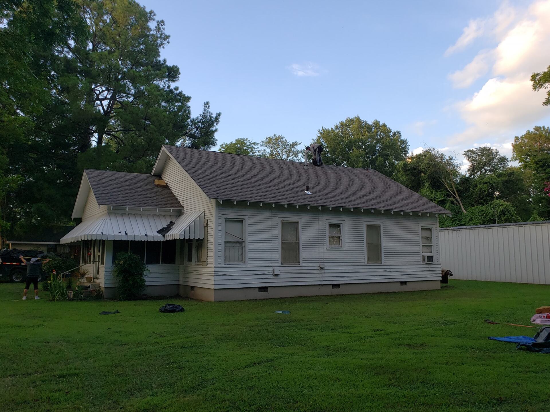 A white house with a gray roof is sitting in the middle of a lush green field.