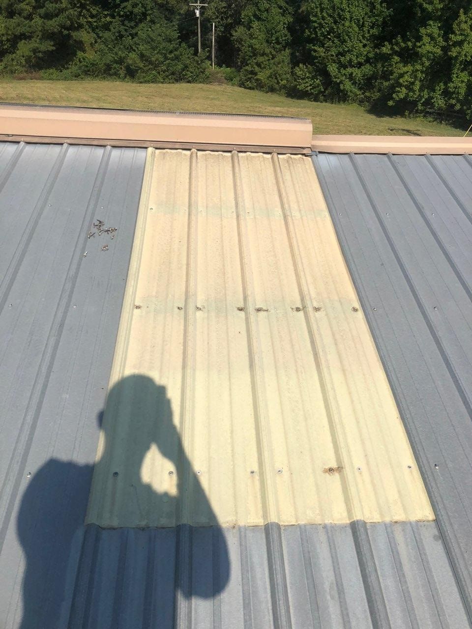 A shadow of a person is cast on a metal roof.