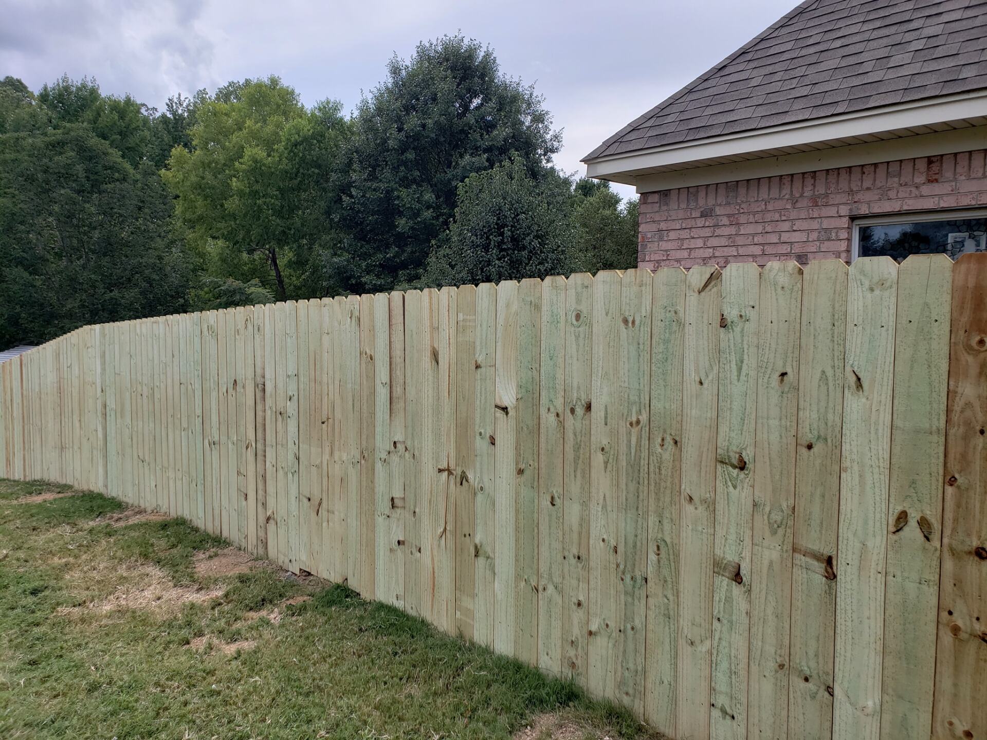 A wooden fence is in front of a brick house.