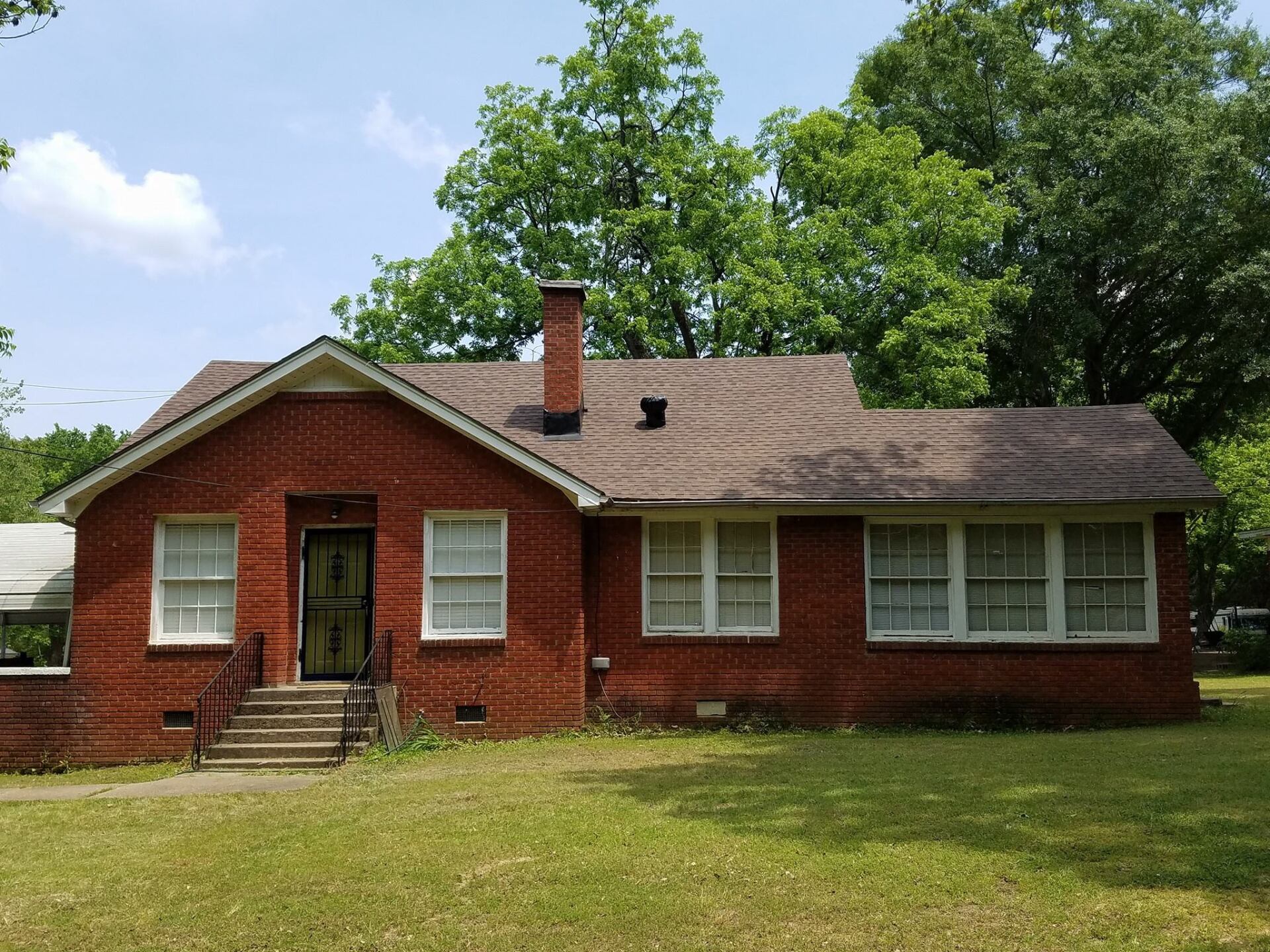 A red brick house with white windows and a brown roof