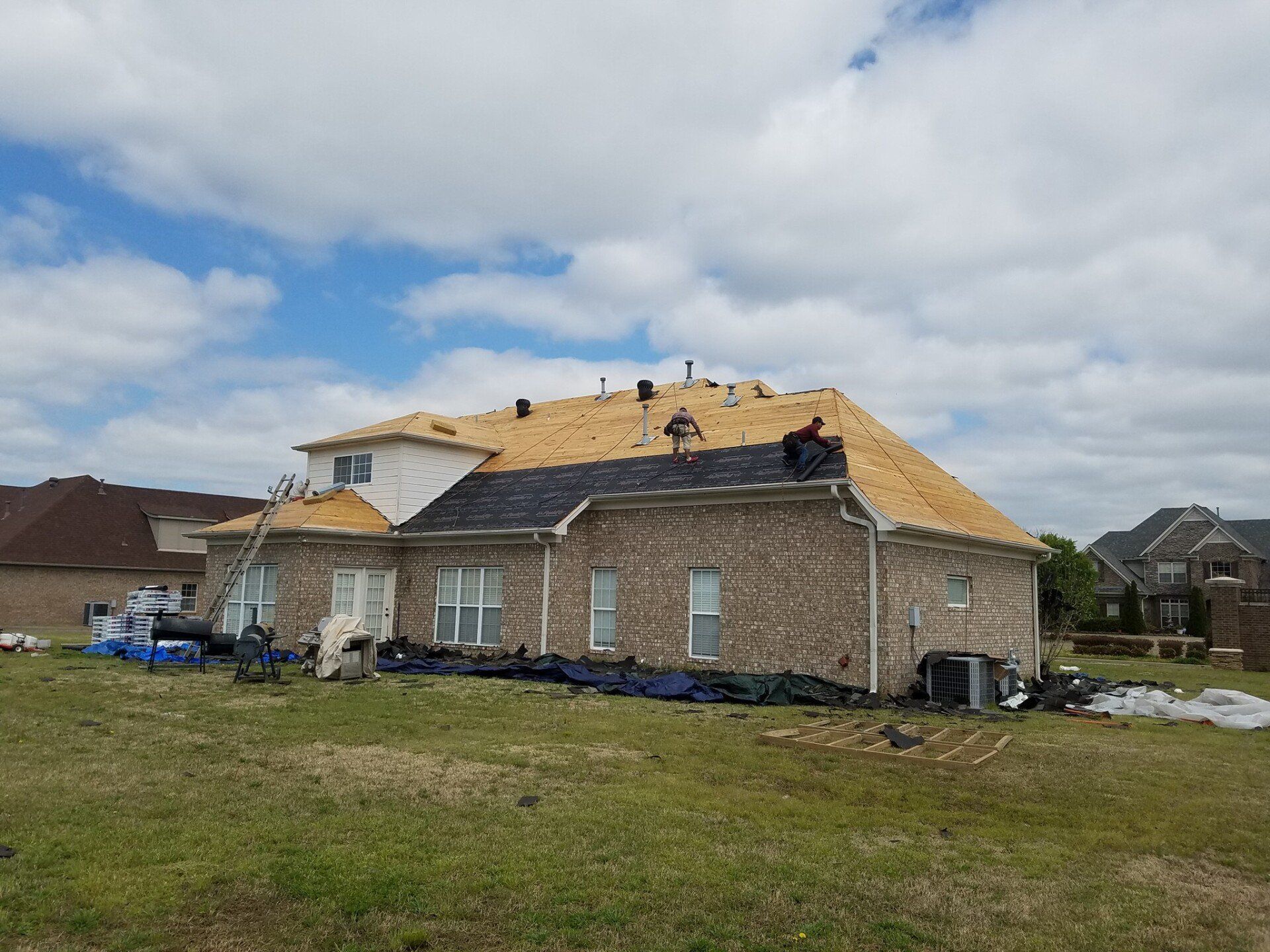 A large brick house is being remodeled with a new roof.