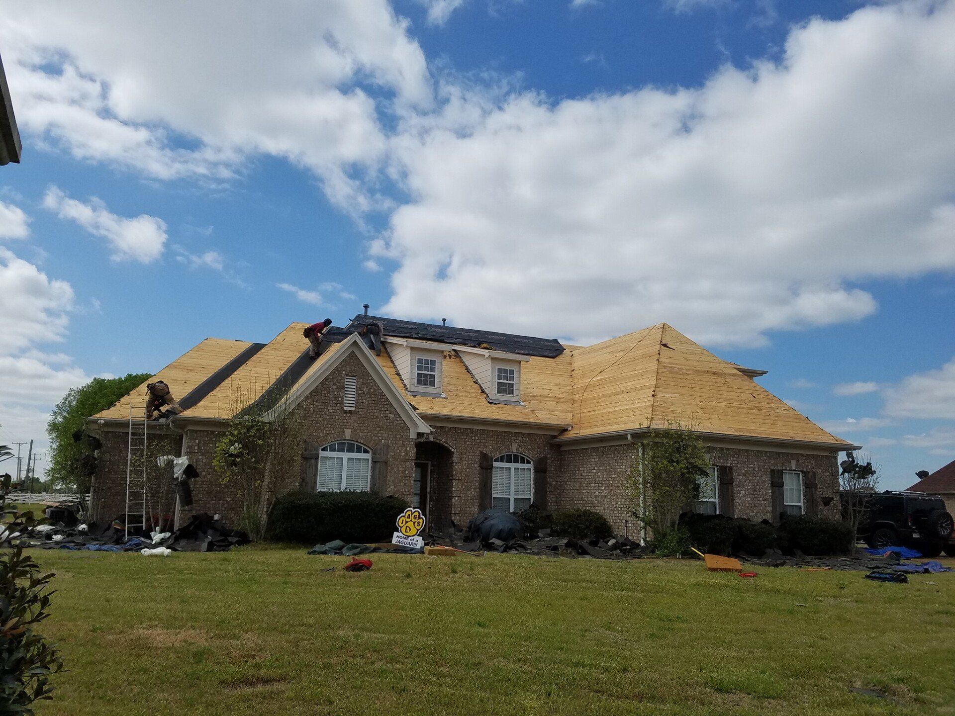A large brick house is being remodeled with a new roof.
