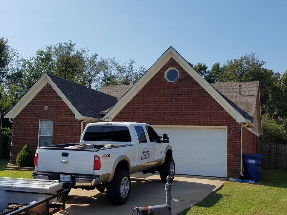 A white truck is parked in front of a brick house