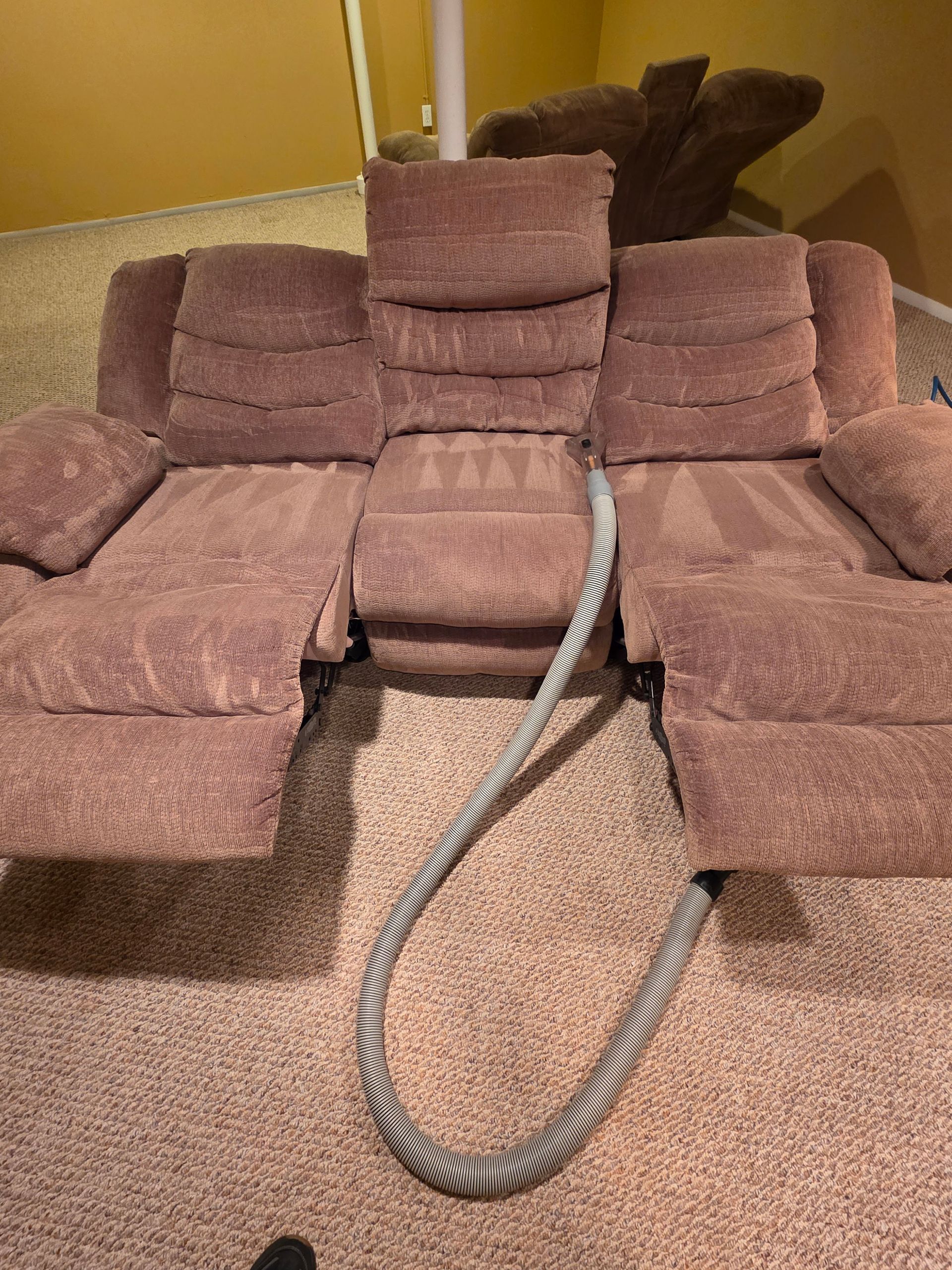 Brown plush chair/sofa with a rope draped over the seat in a carpeted room
