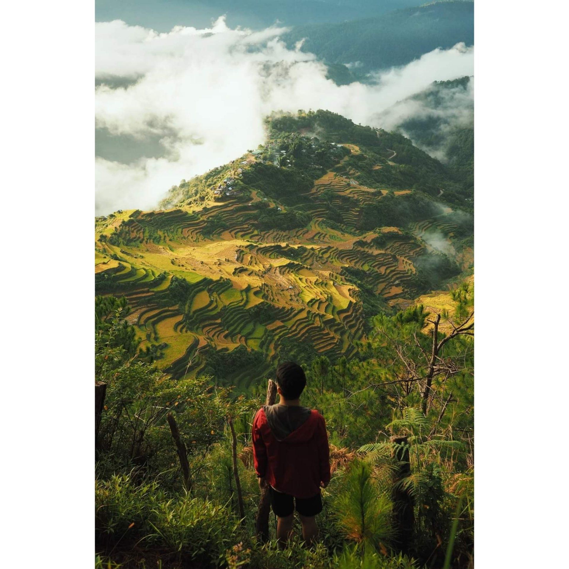 A man is standing on top of a mountain taking a picture.