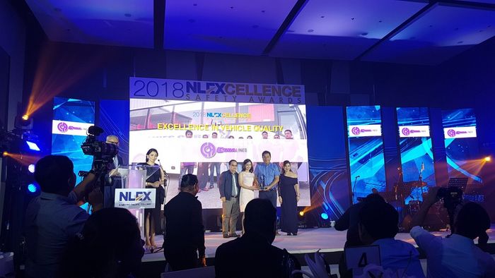 A group of people are standing on a stage in front of a large screen.
