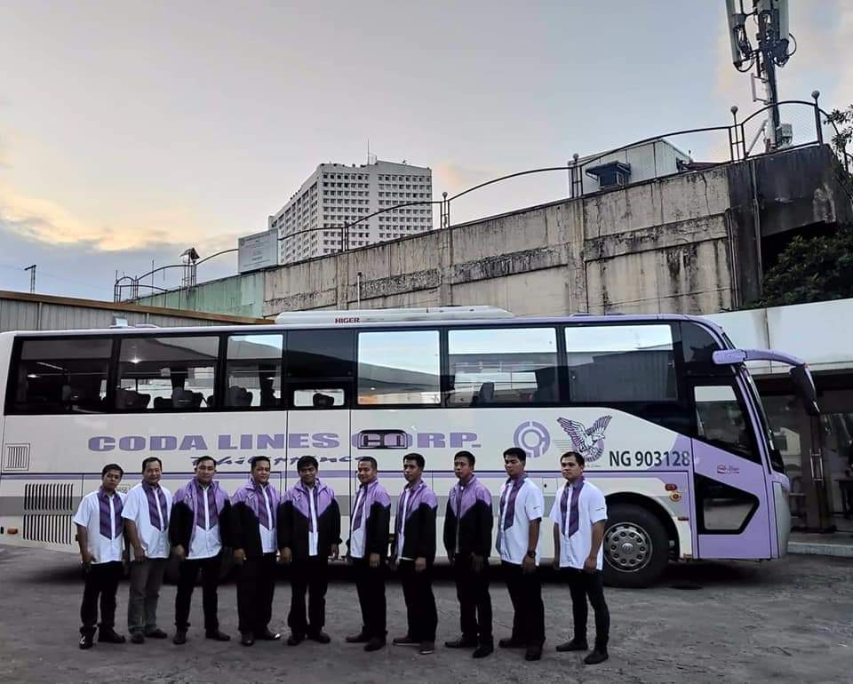 A group of men standing in front of a bus that says good lines corp