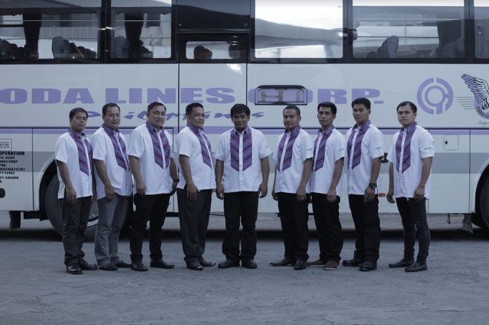 A group of men standing in front of a bus that says odalines corp