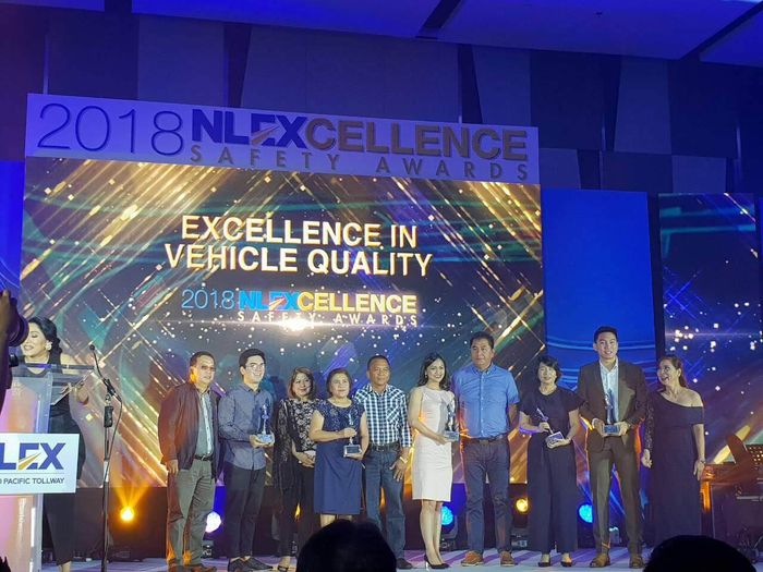 A group of people standing in front of a sign that says excellence in vehicle quality